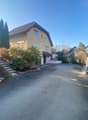 2 story house, beige walls, brown roof, paved driveway, front stairs, hedges, side gate