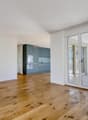 Empty living room with white walls, wooden floor, glass sliding doors leading to a balcony