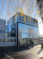 Modern office building, glass facade, black trim, 4 floors, parking lot in front