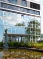 modern office building with glass facade, pond with sculpture in front