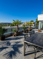 Stone floor, round table, chairs, palm trees, distant buildings, mountain range