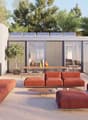 Modern outdoor living space with a terrace, solar panels on the roof, large windows, and a view of the surrounding landscape.