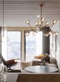 Cozy living room with large windows overlooking a snowy landscape, wood-paneled ceiling, modern chandelier, leather armchair, round coffee table, and a fireplace