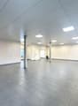 Empty room with grey tiles, white walls, square ceiling lights, and windows with blinds.