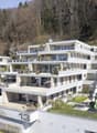 Modern multi-story building with multiple balconies, green roofs, and a playground