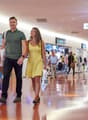 A man and a woman walking hand-in-hand in a shopping center.