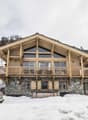 log chalet with wooden balconies, stone foundation, wooden interior, nestled in snowy mountainous landscape