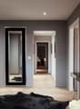 Modern room with gray walls, large mirror, wooden floor, black furry rug, console table with decorative items