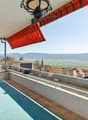 table and chairs, red and white striped awning, blue floor, metal railings, view