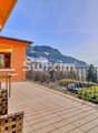 Terrasse spacieuse avec vue sur les montagnes et le lac, équipée de meubles en rotin et baignée de soleil.