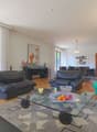 Leather sofas, wooden floor, large windows, balcony, sliding doors, table with fruit
