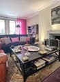 Living room with fireplace, bookshelves, coffee table, couches, lamps, and a rug