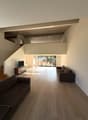spacious room, wooden floors, modern furniture, large windows, living room setting, staircase