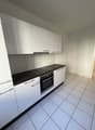 Modern kitchen with white cabinets, black countertops, white tiles, electric stove, oven, open layout, no visible washing machine or dishwasher