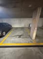 Number 45 parking space, grey car parked, yellow markings on floor, concrete walls, drainage grate