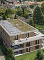 Modern multi-story house with a green roof, solar panels, and a balcony.