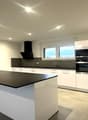central island, black countertop, white cabinets, built-in appliances, sink, modern design