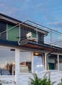 white house, black roof, balcony with metal railing, glass windows, white fence