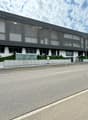 Modern office building with glass windows, concrete planters in front, road next to the building