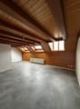 empty room, wooden ceiling, wooden walls, gray tiles, three windows, white radiator