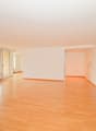 Empty room with wooden floors, white walls, sliding doors, and windows with white curtains