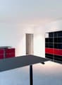 empty room, white walls, gray floor, black desk, red and black cabinets, black and red shelves