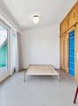 Empty room with a bed, large windows, balcony, wooden ladder, wooden cabinets, white walls, ceiling lamp