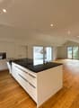 modern kitchen with island, black granite countertop, white cabinets, wooden floor, large windows, balcony