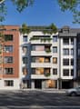 Modern apartment building with brick and concrete facade, multiple balconies, and green rooftop