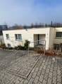 modern apartment building, white exterior, brick driveway, fenced garden, handrail on steps
