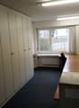 empty room, white cabinets, desk, chair, window, radiator, blue carpet