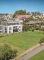 Multiple residential houses in a hilly neighborhood, large front and back yards, some with balconies, greenery and wide roads
