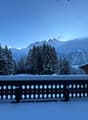 Snow covered balcony railing, snowy landscape, winter mountains, trees, wooden chalet