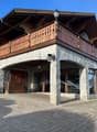 Rustic mountain house with wooden balcony, brick and stone construction, double entrance, security camera, brick driveway