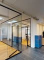 modern office room, glass walls, white desk, wooden floor, wooden cabinets, coffee machine