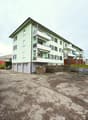 4 story building, green exterior, balconies, garage, parking lot