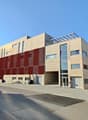 modern building, red panels, many windows, glass door, paved road