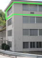 2 story building, large windows, driveway, green outline