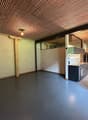Empty kitchen with gray floor, white walls, wooden ceiling, sink, cabinets