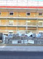 Building under construction, scaffolding, multiple windows, materials stacked in front