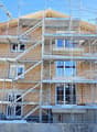 House under construction, brick walls, glass windows, scaffolding, multiple floors