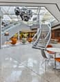 modern interior with white and orange chairs, white tables, large staircase, escalator, glass ceiling