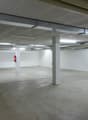 empty parking place, white walls, gray floor, ceiling with metal frames, fire extinguisher, white ceiling with fluorescent lamps