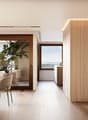 Dining room with wooden floor, large windows, dining table, chairs, wooden wall, artwork, plants