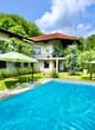2-story villa, white exterior, red roof, large pool, patio, fence, trees, umbrellas, stairs