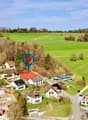 Aerial view of a neighborhood with several houses, green fields, and a winding path.