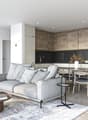 Open plan, grey couch, wooden table, wooden chairs, white cabinets, black counter-tops, oven