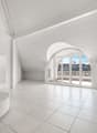 Spacious attic living room with white walls, large arched windows providing a view, and a tiled floor.
