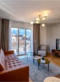 leather couch, coffee table, TV, armchair, chandelier, rug, balcony