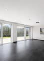 large sliding glass doors, black tiled floor, white walls, painting on wall, view of grassy area